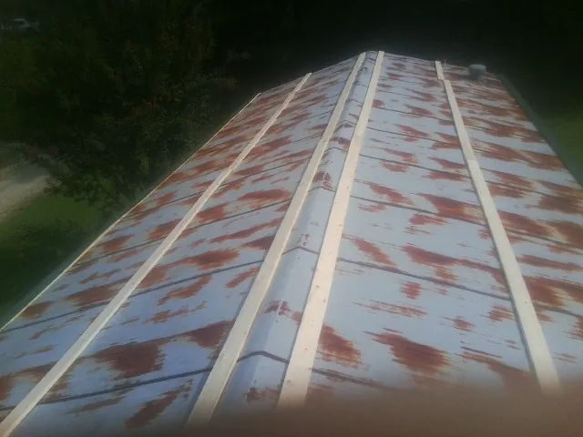 Rusted metal roof panels with new wood purlins before replacement — Storm Damage Roof Repair in Rollins by Roofing Brothers