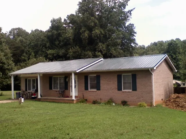 Gray metal roof on a brick ranch house with a side carport in Rollins