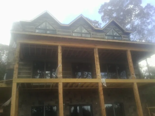 Dormers and porch framing on a large log home under construction — Roof Coating work by our crew in Rollins