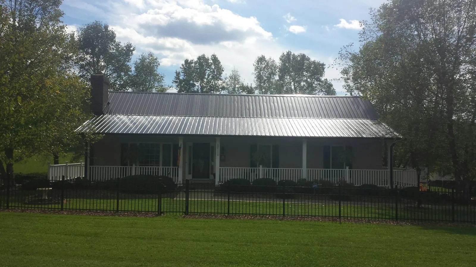 Gray metal roof on a brick ranch with a full width front porch — Gutter Guard Installation work by our crew in Rollins