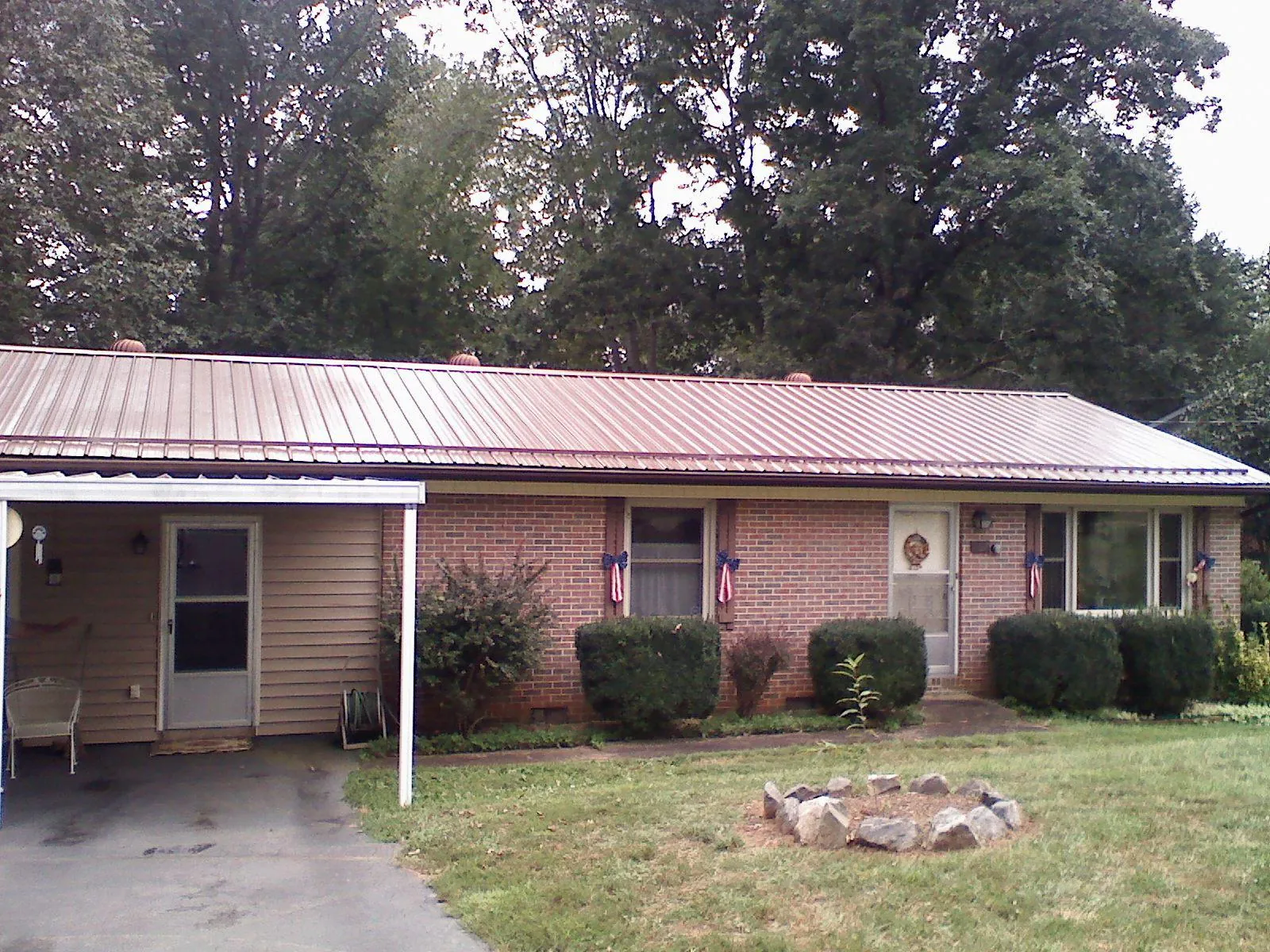 Bronze metal roof and carport on a brick ranch home — Roof Repair work by our crew in Rollins