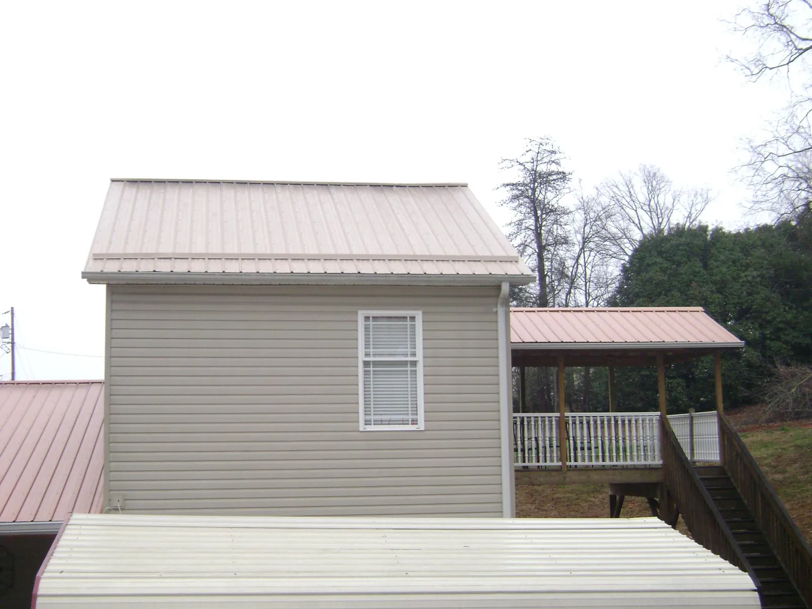 Tan metal roofs on a two story addition and attached porch, from a Roof Replacement job in Rollins